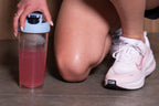 A person holding a bottle of WeBilt electrolytes on a concrete floor.